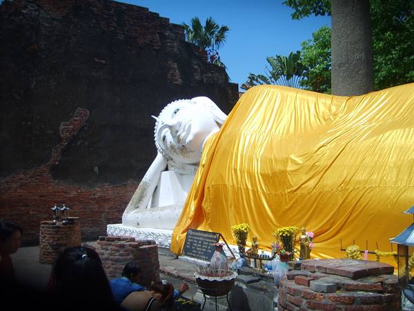Reclining Buddha draped in yellow cloth among brick ruins, Ayutthaya