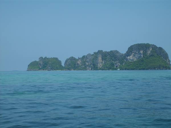 Limestone islands covered with vegetation above turquoise water, hazy light