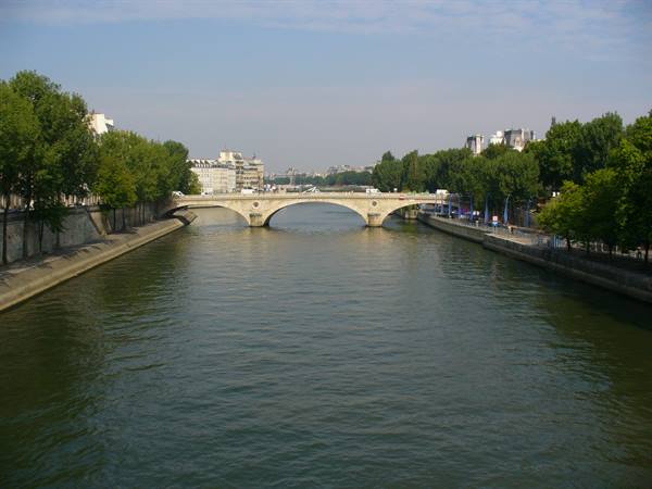 Stone arch bridge over the Seine, tree-lined sunny quays in Paris