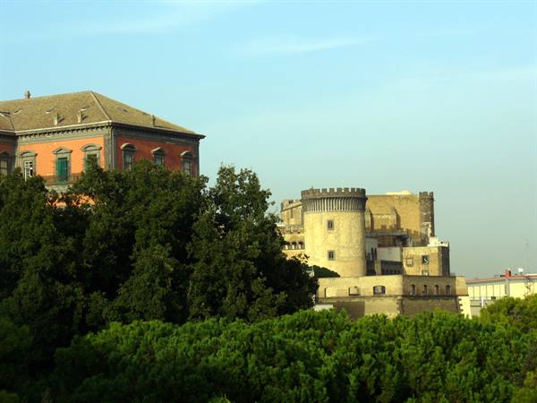 Orange palace and crenellated tower of Castel Nuovo among Naples pines