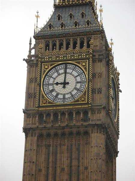 The golden clock face of Big Ben in London against a grey sky
