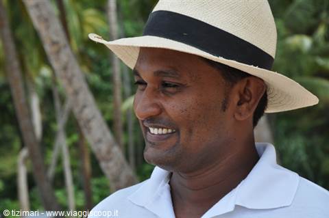 Smiling man in straw hat and white shirt among tropical palm trees