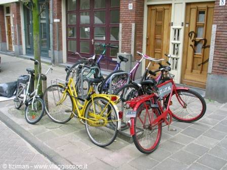Colorful bicycles parked by brick buildings and wooden doors, paved street