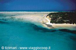 Turquoise lagoon with white sandbar and green vegetation on the coast