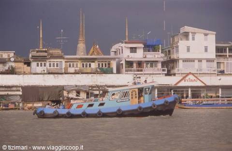 Blue boat on the Chao Phraya river, Wat Arun spires behind, Bangkok