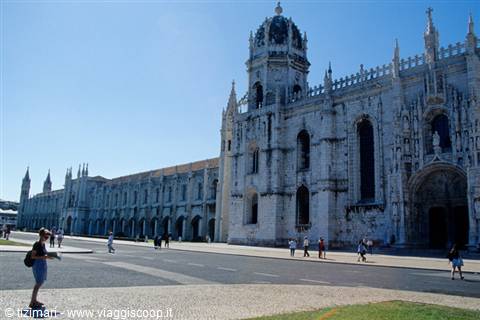 Tourist poses before the Jerónimos Monastery in Lisbon, pale stone under bright sun
