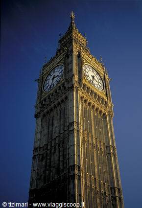 Big Ben's golden stone clock tower lit against a dark blue sky, London