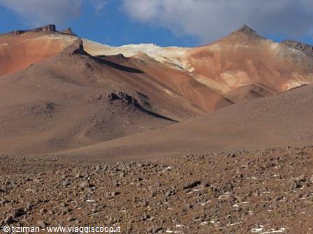 Multicolored volcanic rock mountains above a boulder-strewn slope