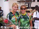 Two athletes in green jerseys with medals beside flowers, goodwill ambassadors