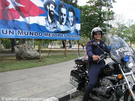 Police officer on a motorcycle beside a political billboard in Havana