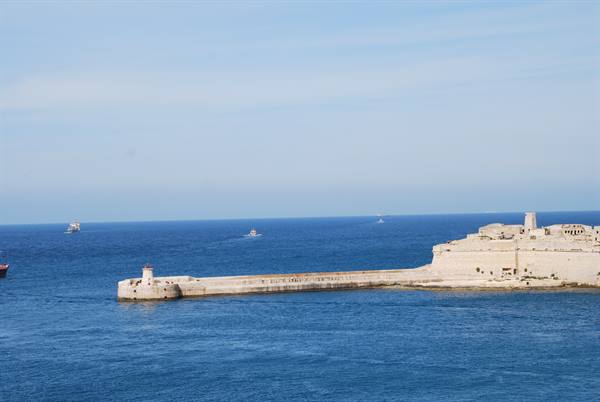 Valletta stone breakwater with lighthouse, boats on the blue sea
