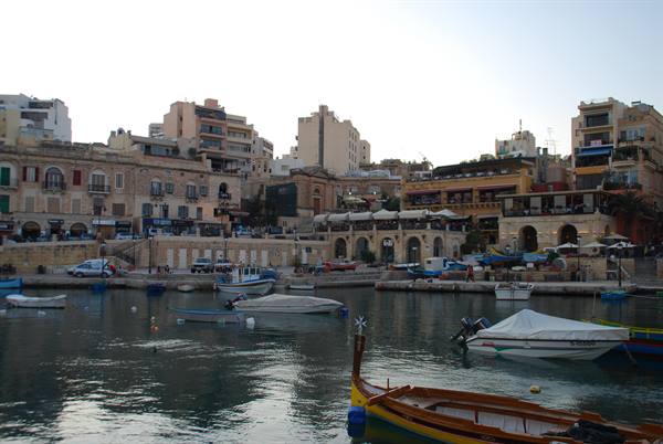 Fishing boats moored at Spinola Bay, limestone buildings, evening light