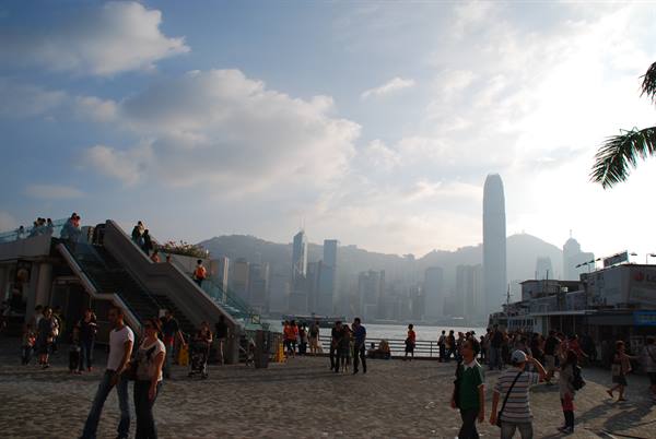 Visitors at Tsim Sha Tsui pier facing the harbor and skyscrapers