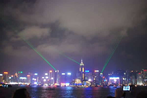 Green laser beams over Hong Kong's illuminated skyscrapers at night