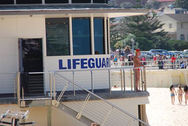 Bagnino in piedi sulla torre LIFEGUARD, spiaggia affollata di Bondi, Sydney
