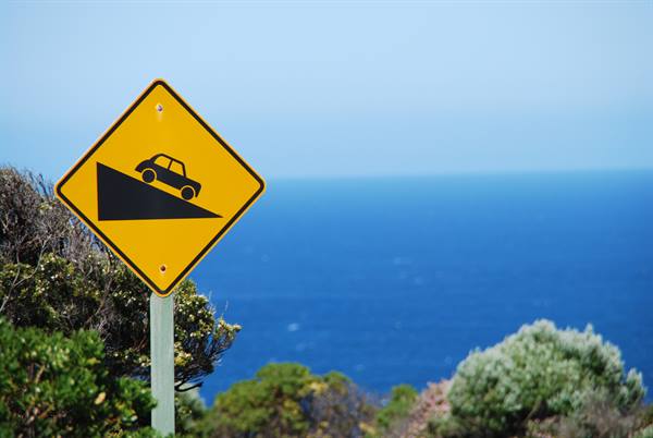 Cartello giallo di discesa ripida davanti all'oceano a Cape Otway