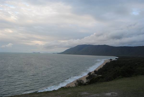 Spiaggia sabbiosa sotto montagne verdeggianti e nuvole, Port Douglas