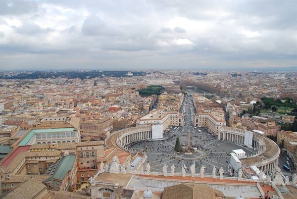 St. Peter's Square in Rome with the colonnade, fountain and rooftops under cloudy skies