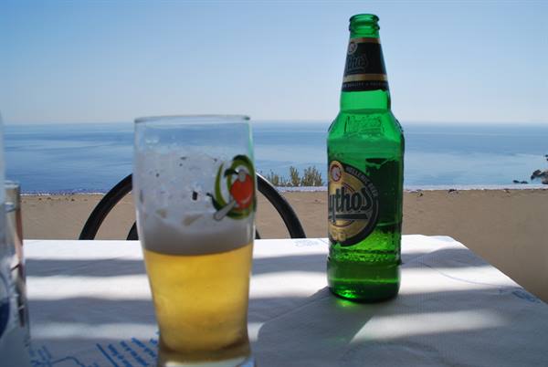 Mythos beer bottle and glass on a table overlooking the sea