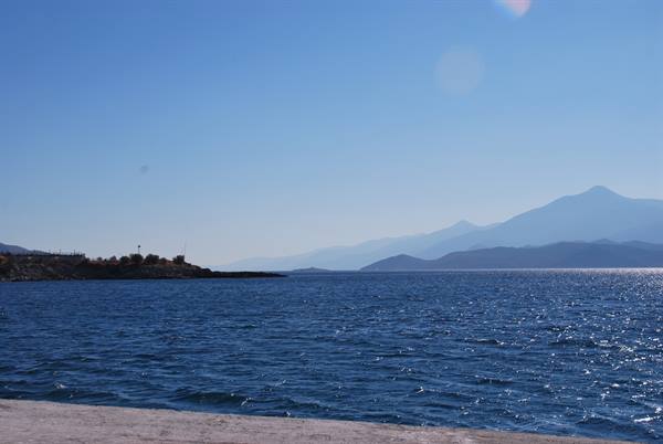 Blue sea with mountains in the background and rocky shoreline