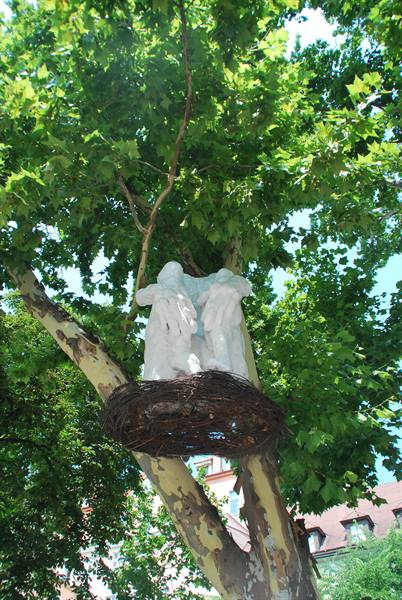 White statue inside a large twig nest on a tree
