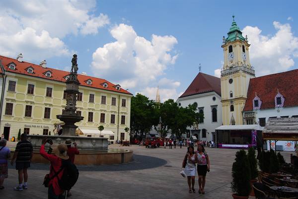 Tourists photograph the baroque fountain in Bratislava's Old Town square beside the church