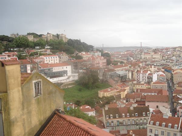 Lisbon: red rooftops, São Jorge Castle and 25 de Abril Bridge under grey sky