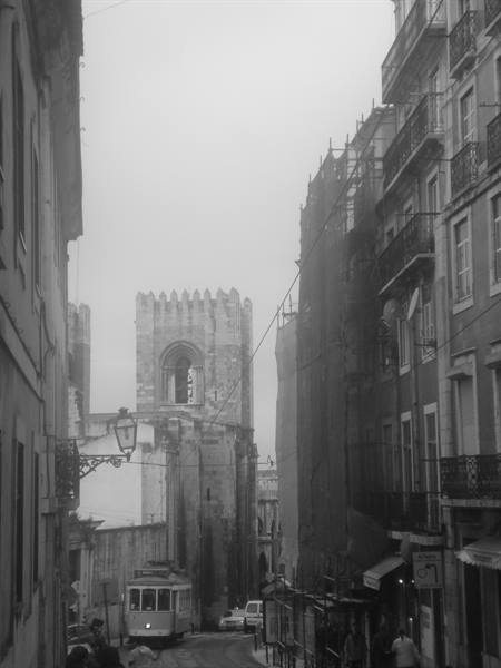 Tram climbing steep street toward Lisbon Cathedral Sé, black and white