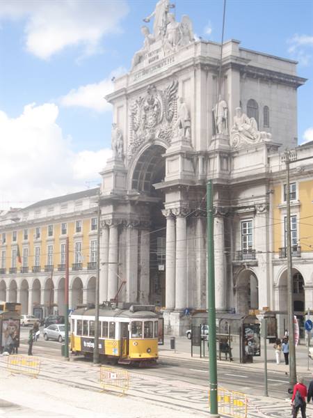 Yellow tram passing under the Rua Augusta Arch in Lisbon