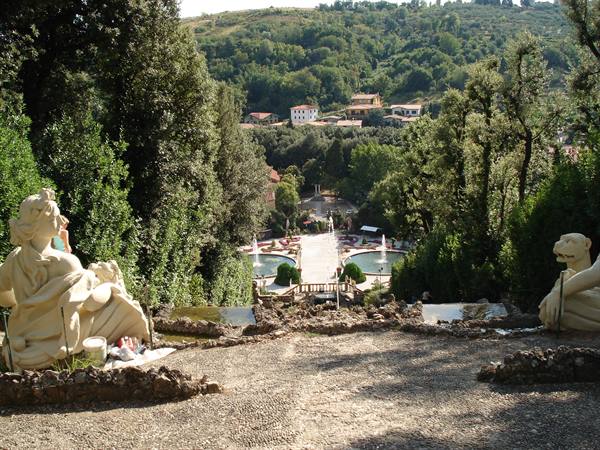 Stone statues overlook fountains and tree-lined avenue at Collodi