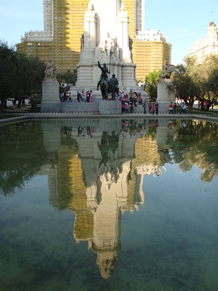 Tourists around the Cervantes monument at Plaza de España, Madrid, reflected in the pond