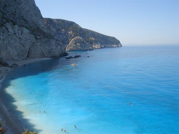 Swimmers in turquoise water beneath white limestone cliffs at Porto Katsiki