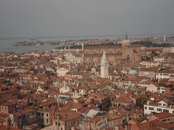 Red rooftops of Venice with churches and bell towers under grey sky, diffused light