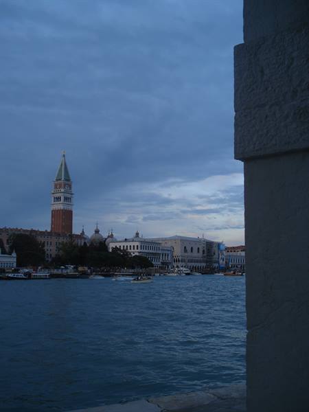 Bell tower and palaces along the lagoon, framed by stone pillar, dusk light