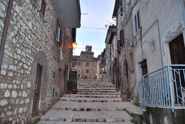 Stone staircase between old stone houses, lit lamps in the medieval village