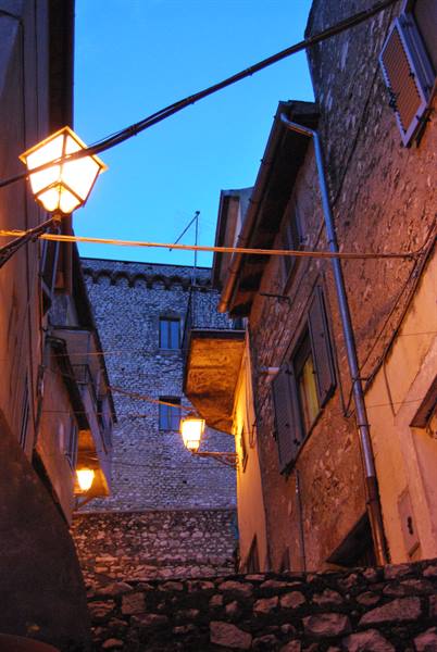 Stone alley with lit lanterns between old houses at dusk