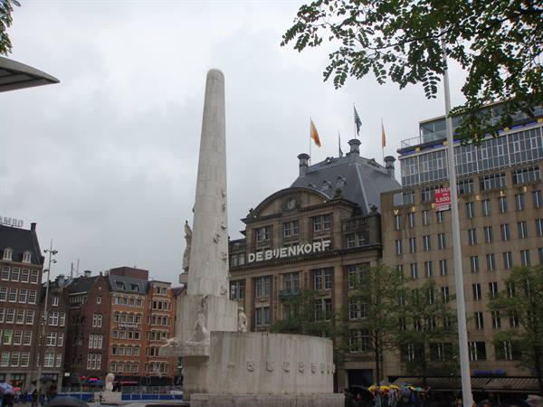 White stone National Monument at Dam Square, De Bijenkorf department store behind