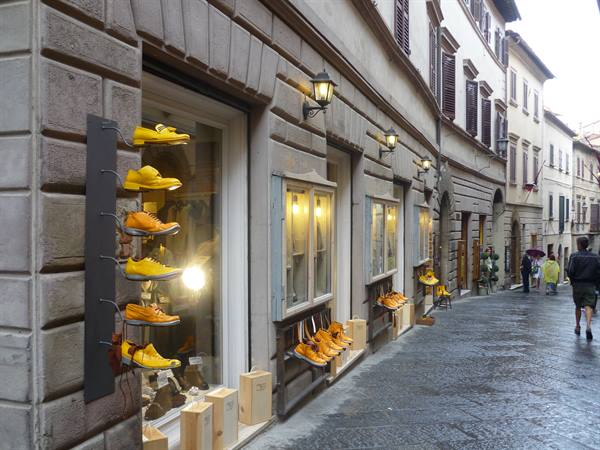 Shoe shop with yellow shoes in window, uphill stone street, Montepulciano