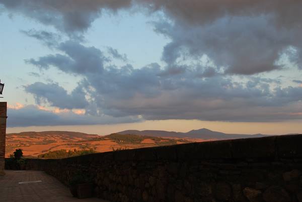 Ploughed hills at dusk beyond a stone wall in Val d'Orcia