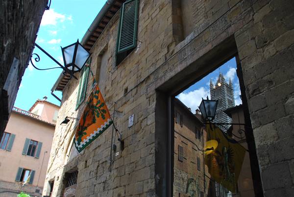 Siena: the Duomo reflected in a stone archway, contrada flags and lantern