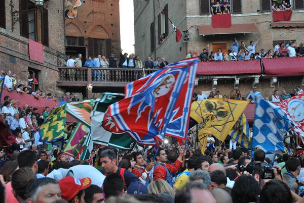 Contrada flags waving over the crowd in Siena's Piazza del Campo
