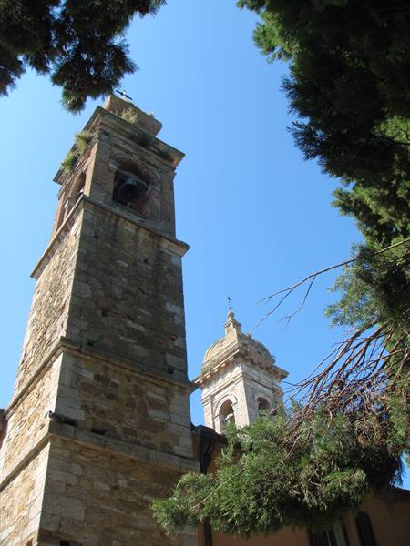 Stone bell tower and baroque dome framed by trees in Montepulciano