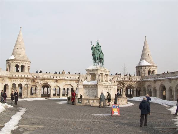 Bronze equestrian statue between conical towers of Fisherman's Bastion, snow on ground