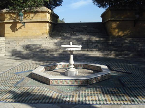 Marble fountain on eight-pointed zellige tilework, stone steps and green lantern