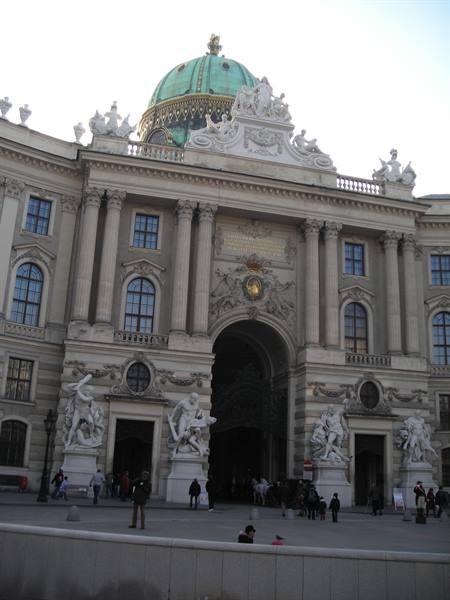 Hofburg in Vienna: baroque facade with green dome, marble statues and tourists