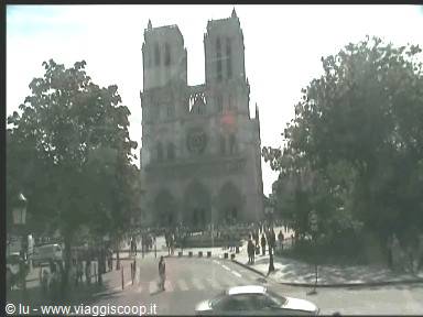 Tourists walk in front of Notre-Dame's gothic facade among trees
