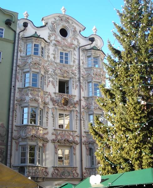 Rococo stucco façade of Helblinghaus in Innsbruck beside a decorated Christmas tree