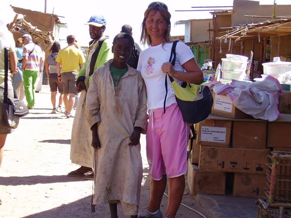 Tourist with a boy in a djellaba at a sunny street market