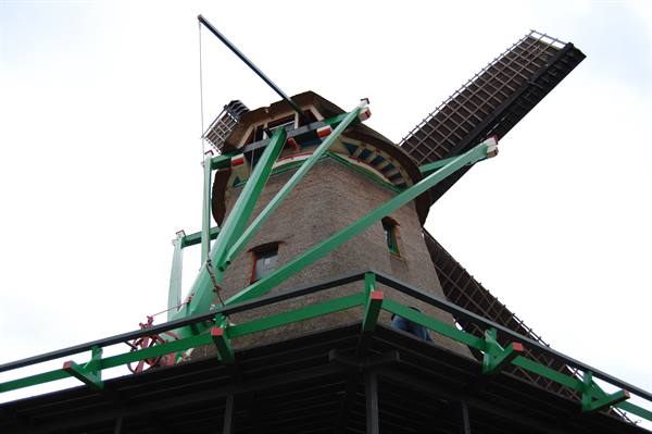 Brick windmill with wooden sails and green crossbeam