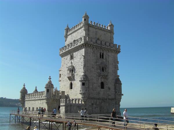 Tourists on the wooden walkway leading to the stone Belém Tower